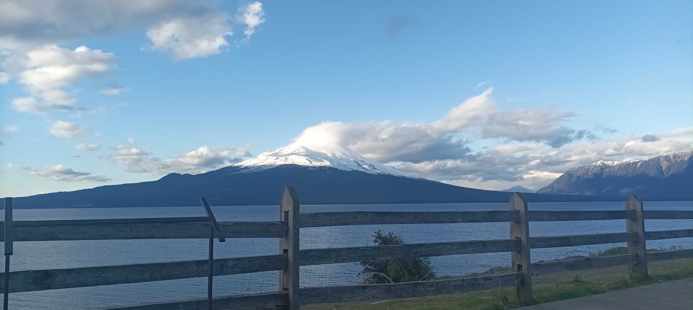 Volcán nevado, lago y paisaje rural del sur de Chile